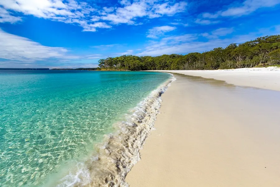 Turquoise water against a white sand beach backed by bush