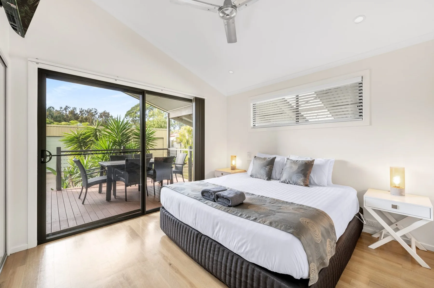 King bed made up beside sliding doors that open onto the deck
