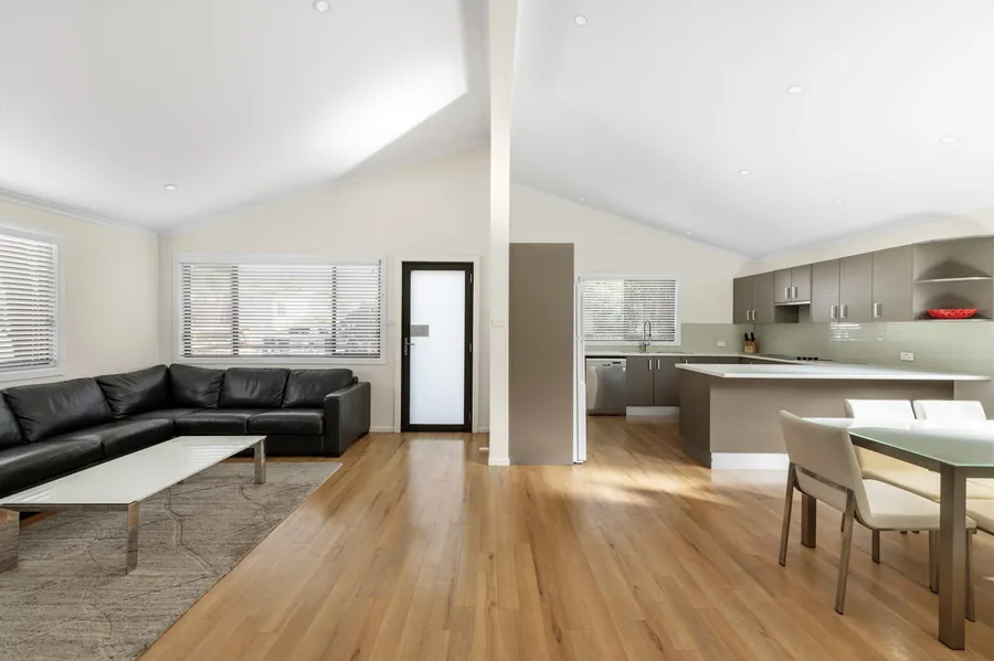 Open plan living and kitchen with a corner lounge, timber floor and a dining table