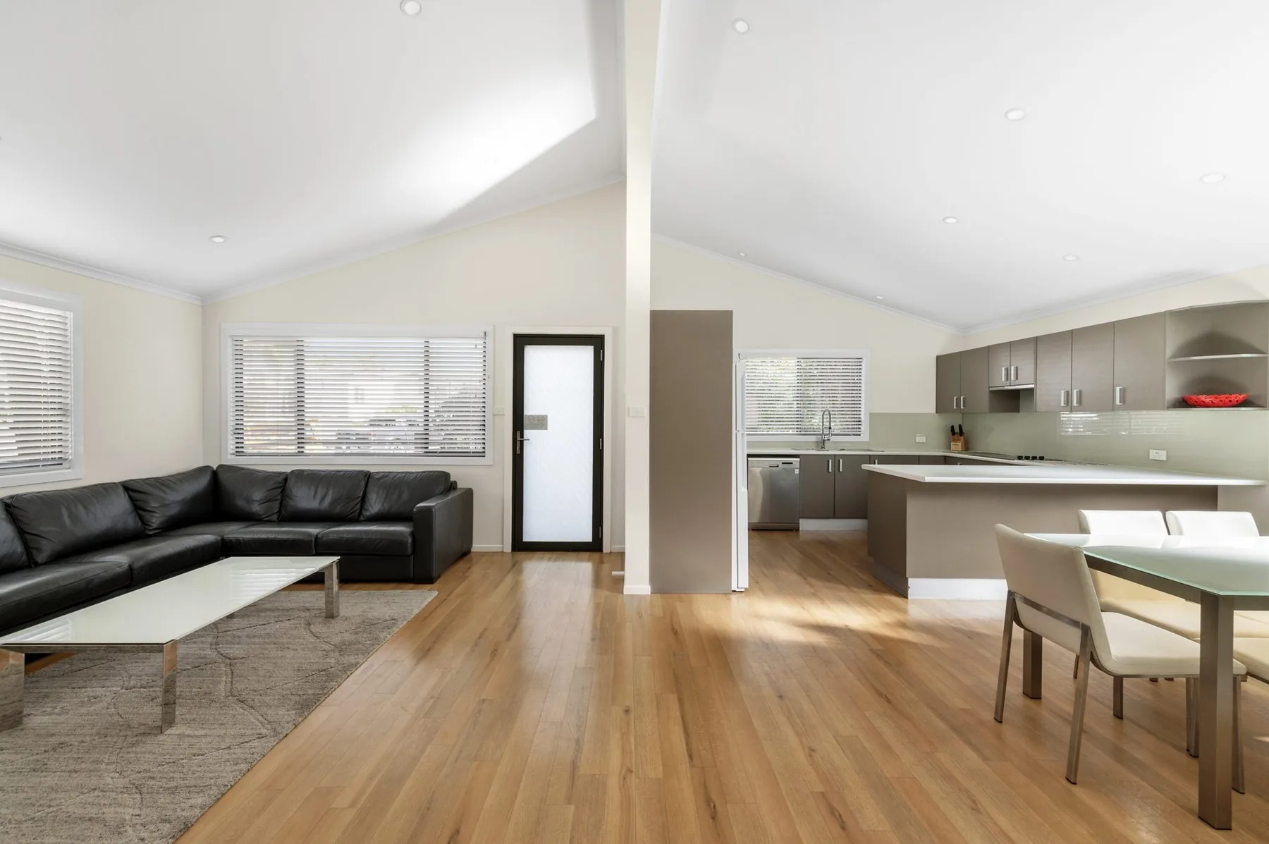 Open lounge with a modular sofa, the kitchen island and dining table beyond