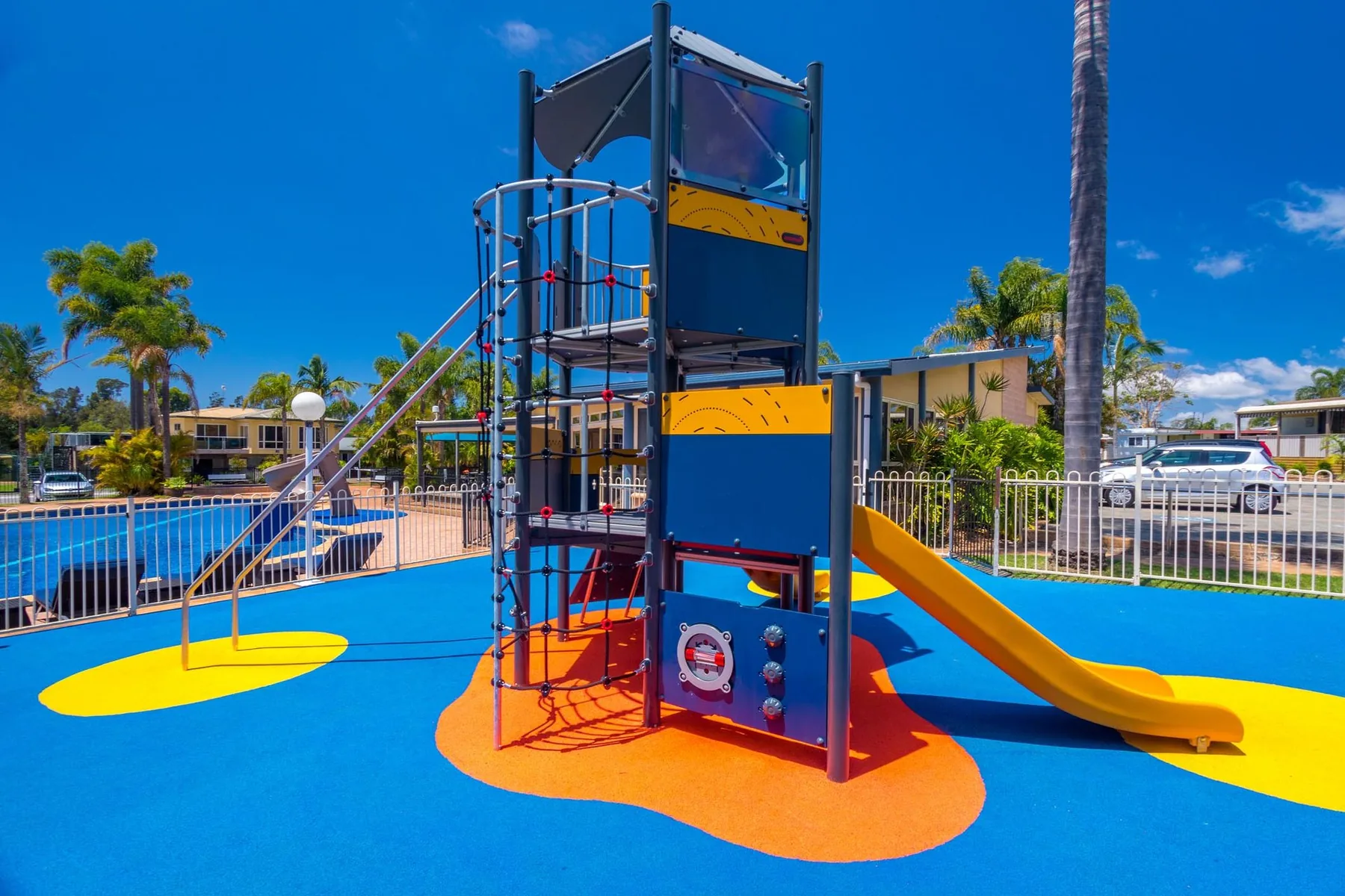 Brightly coloured climbing frame and slide inside the fenced playground