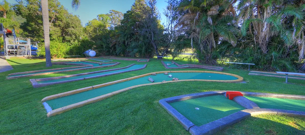 The mini golf course, its putting lanes edged in timber under tall trees