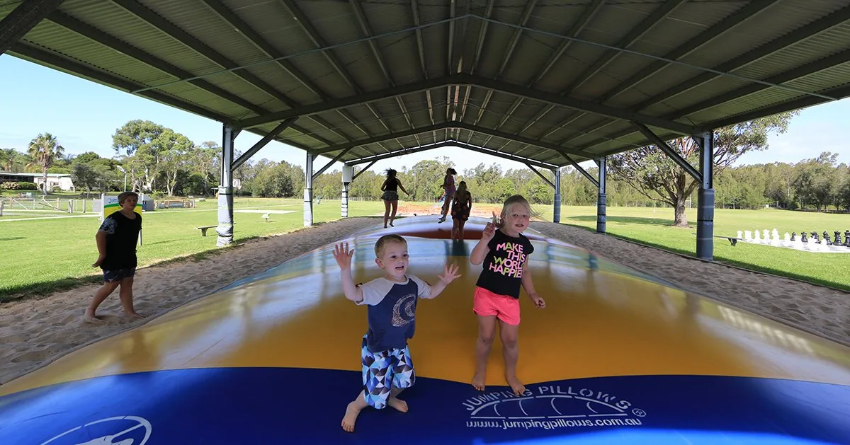 Two children bouncing on the undercover jumping pillow