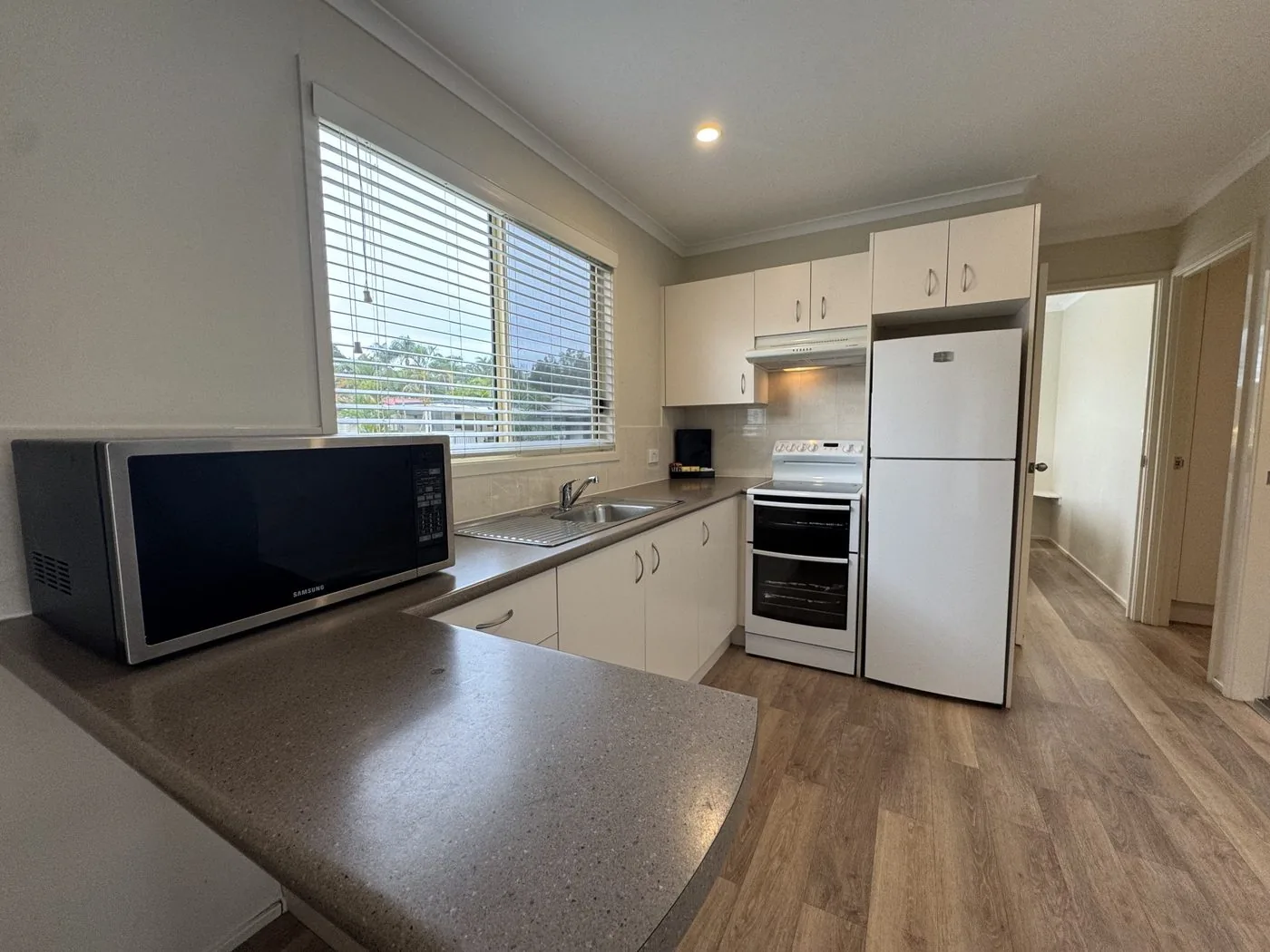 Kitchen bench with a microwave, sink and fridge alongside
