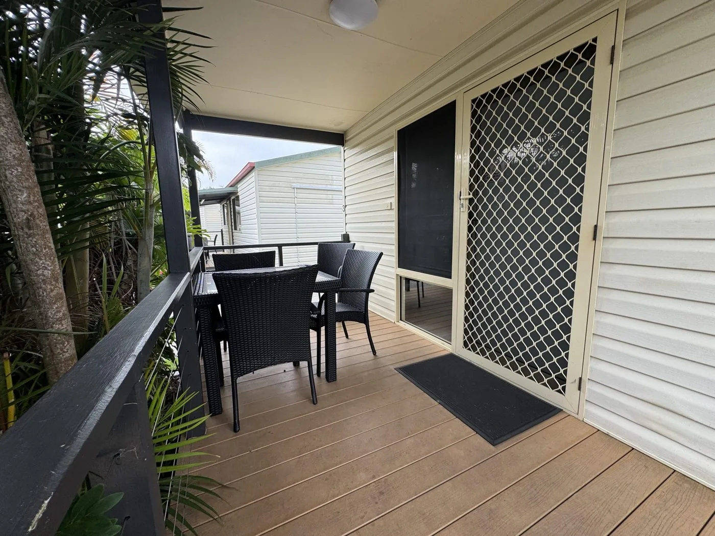 Veranda with an outdoor setting beside the cabin door and a palm overhead