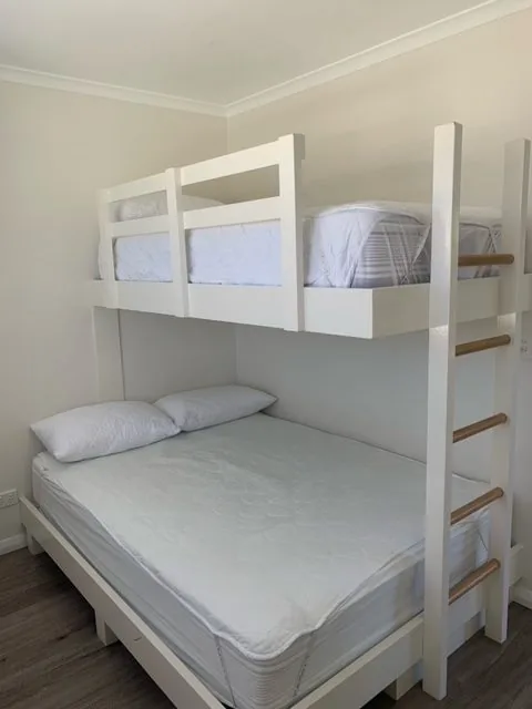 Bunk beds with a ladder against a white panelled wall