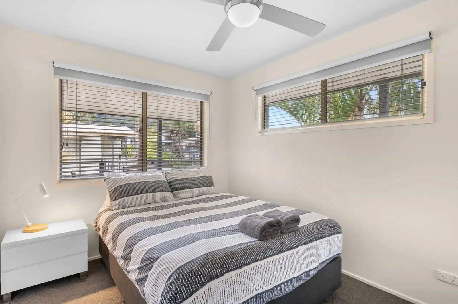 Main bedroom with a queen bed made up and towels folded at its foot