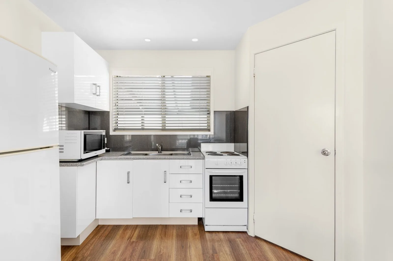 Kitchen run with a microwave, oven and cupboards along one wall