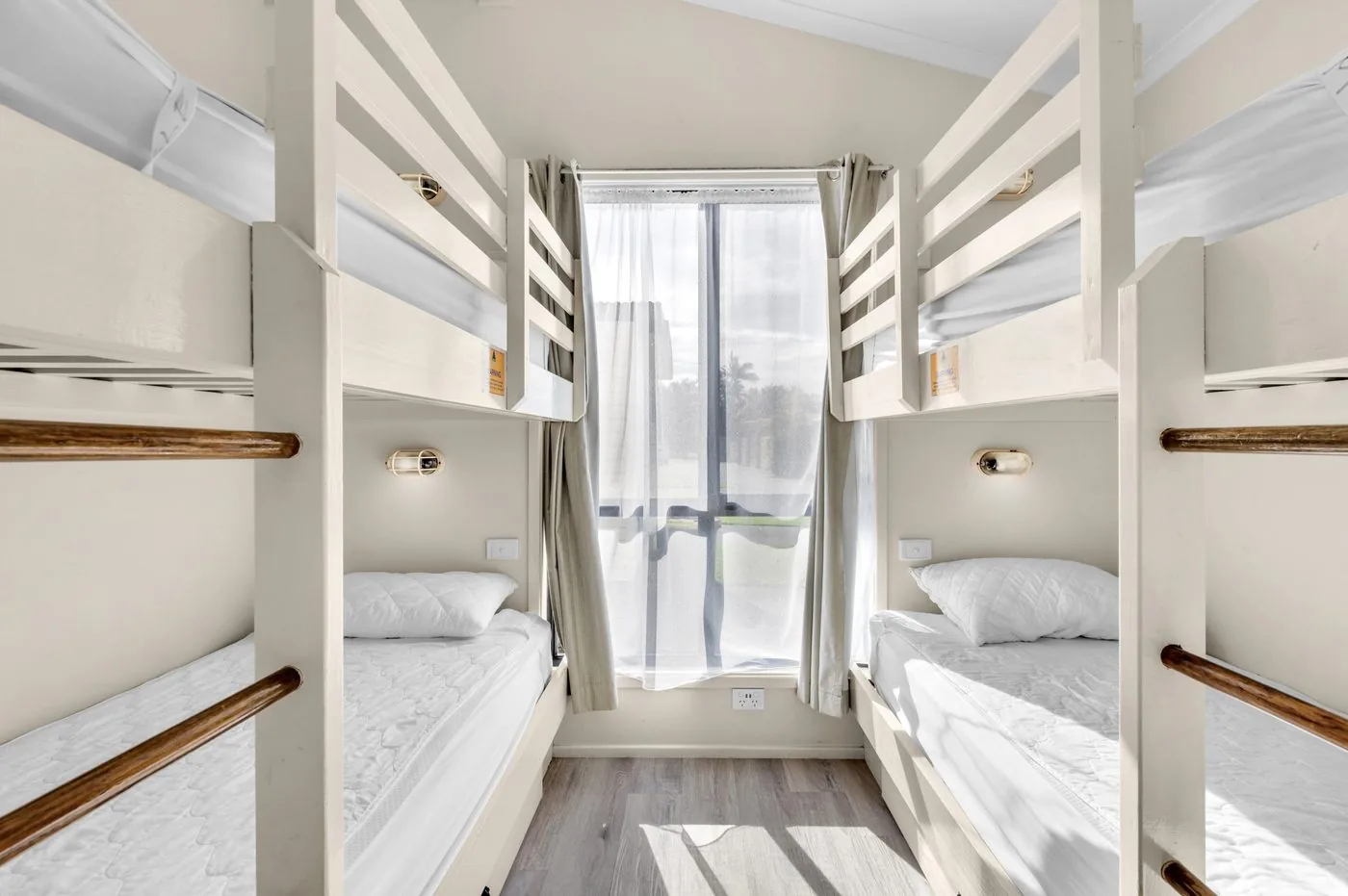 Bunk room with two sets of timber bunks either side of a window