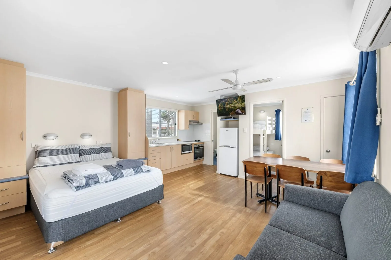 Queen bed in the open living area with the kitchen and sofa beyond