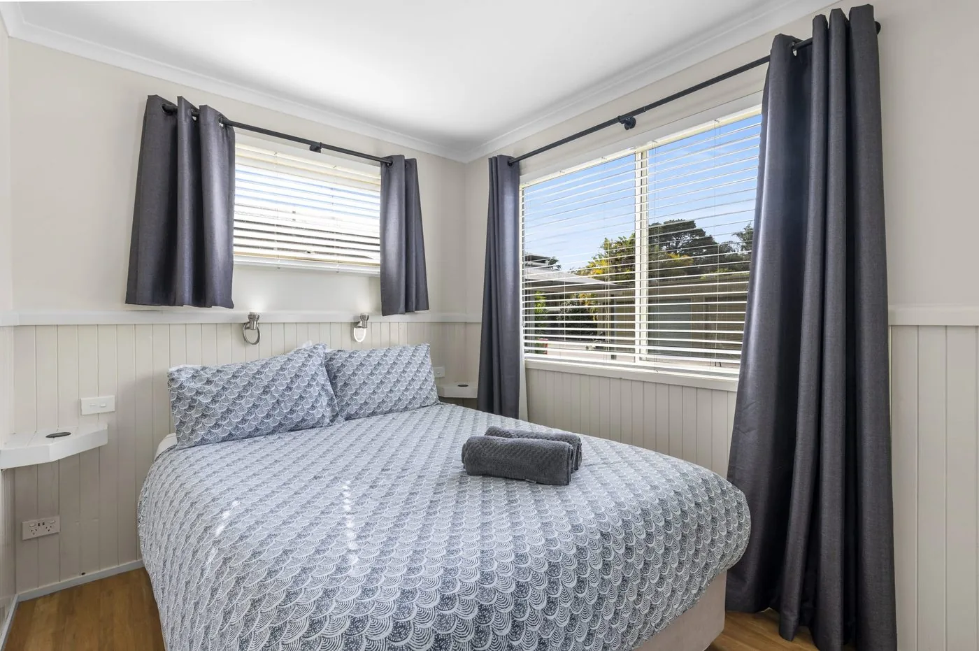 Bedroom with a queen bed made up and floor-length grey curtains