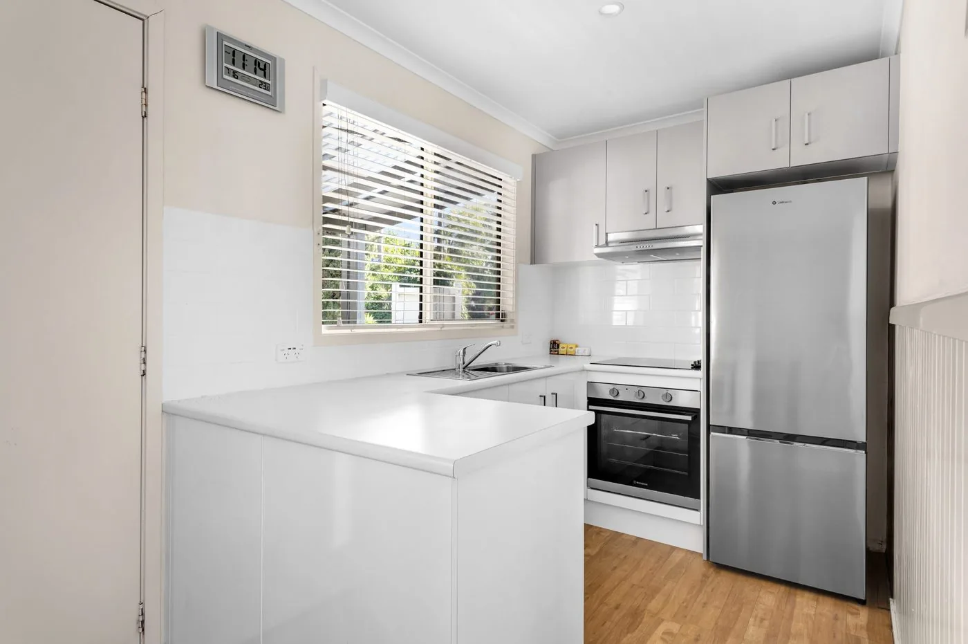 Kitchen with a stainless fridge, wall oven and a window above the sink
