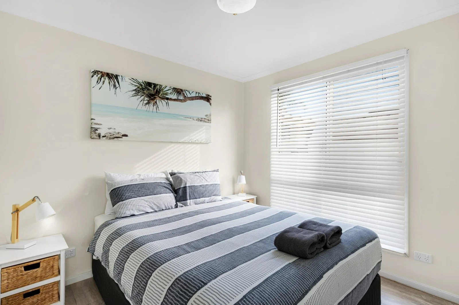Main bedroom with a queen bed made up and a framed print above the bedhead