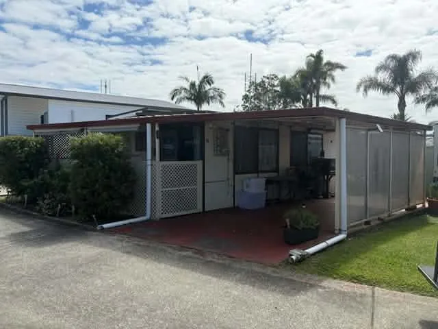 A relocatable home in the park with a carport and a front verandah